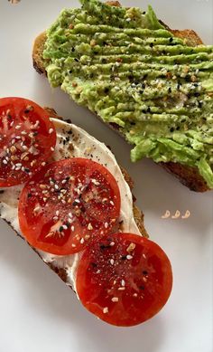 two slices of toast with avocado and tomatoes on them, sitting on a white plate