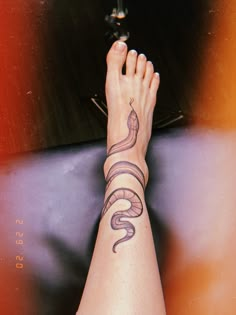 a woman's foot with a snake tattoo on it