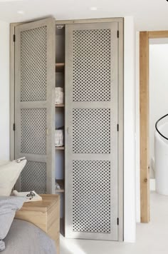 an open closet in the corner of a bedroom with white walls and flooring, next to a bed