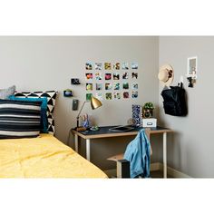 a bed room with a neatly made bed next to a desk and wall hangings