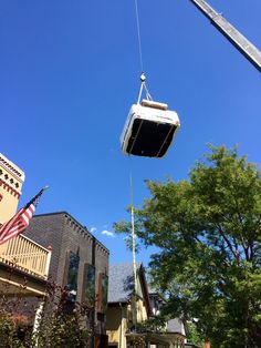 a cable car being lifted by a crane in front of some buildings and an american flag