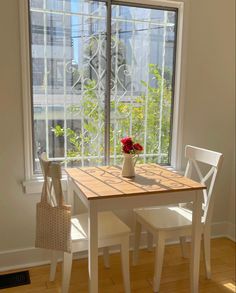 a table and chairs in front of a window with a flower vase on top of it