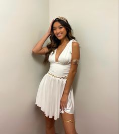 a woman in a short white dress posing for a photo with her hand on her head