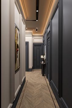 an empty hallway with black doors and white walls is shown in this image, there are paintings on either side of the corridor