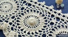 crocheted doily on blue cloth next to glass beads and candlesticks