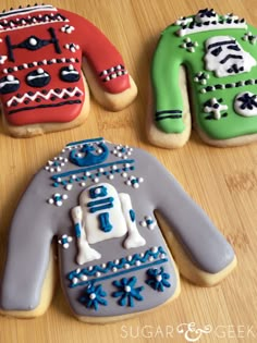 three decorated cookies sitting on top of a wooden table