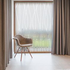 a chair sitting in front of a window with curtains