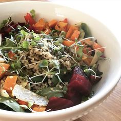 a white bowl filled with lots of different types of food on top of a wooden table