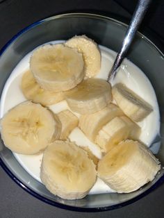 sliced bananas and yogurt in a bowl with a spoon on the counter top