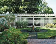 a garden with a white trellis fence in the background