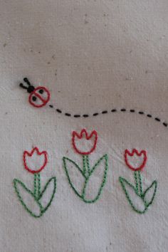 embroidered flowers and ladybug on white fabric