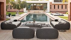 an outdoor living area with couches and tables next to a swimming pool in front of a house