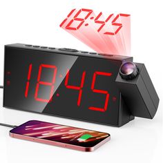 the alarm clock is connected to an iphone and charging it with a red light on top