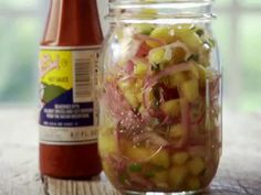 a jar filled with food sitting on top of a wooden table next to a bottle