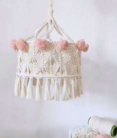 a white macrame with pink pom - poms hanging from the ceiling