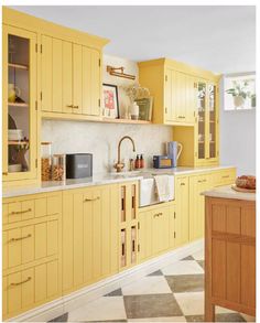 a kitchen with yellow cabinets and marble counter tops