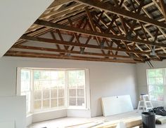 an unfinished room with wood beams and windows