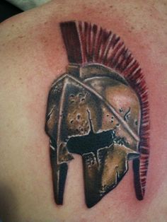 a spartan helmet tattoo on the back of a man's shoulder