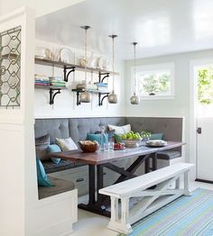 a kitchen with a bench, table and shelves on the wall next to an open door