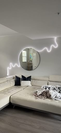 a modern living room with white furniture and large mirror on the wall above the couch