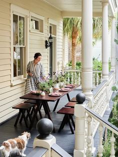 a woman is standing on the porch with her dog