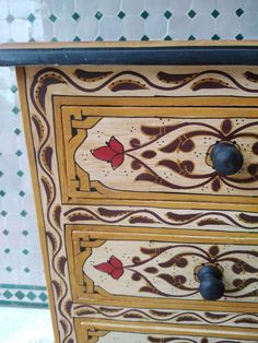 an ornately painted dresser with drawers and knobs