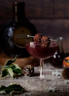 a dessert in a wine glass on a table with pine cones and other holiday decorations