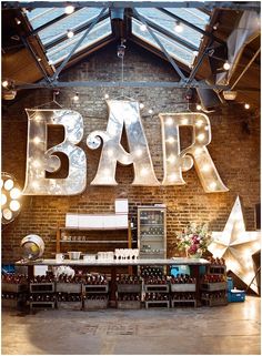 an indoor bar with large letters and lights hanging from the ceiling in front of it