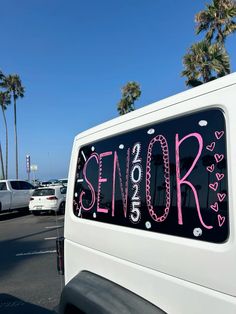 a white truck parked in a parking lot with pink writing on the back of it