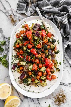 a white platter filled with roasted veggies and tomatoes