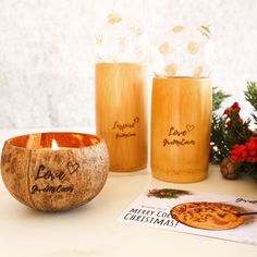 two candles are sitting next to each other on a table with christmas decorations and greeting cards