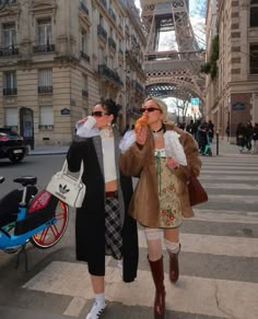 two women walking down the street in front of the eiffel tower