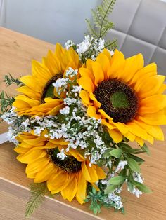 a bouquet of sunflowers and baby's breath sits on a wooden table