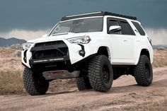 a white four - doored toyota truck driving down a dirt road