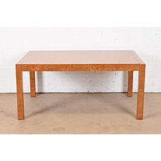 a wooden table sitting on top of a cement floor next to a white brick wall