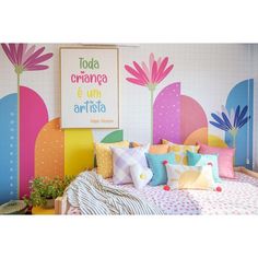 a bed with colorful pillows on it in front of a wall painted with flowers and plants