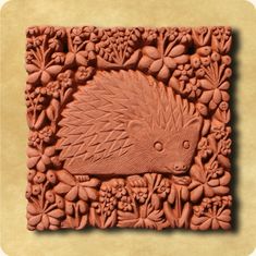 an intricately carved hedgehog in the middle of flowers and leaves on a blue background