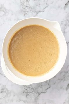 a white bowl filled with brown liquid on top of a marble counter