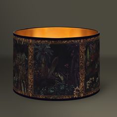 a black and gold lamp shade with an image of tropical plants on the inside of it