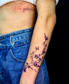 a woman's stomach with a small flower tattoo on her left arm and the word love yourself written in cursive writing