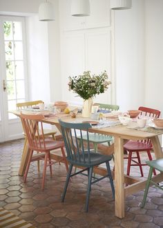 a dining room table with chairs and a vase filled with flowers on top of it