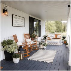 a porch with rocking chairs and potted plants on the front porch, along with an area rug