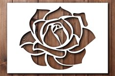 a paper cutout of a rose on a wooden background