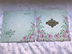 two cards with pink flowers on them sitting on a bed