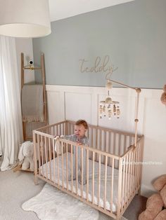 a baby in a crib with teddy bears and a lamp on the wall behind it