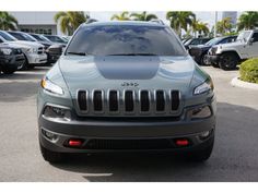 the front end of a gray jeep parked in a parking lot