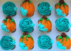 twelve cupcakes decorated with blue frosting and orange icing, arranged in a box