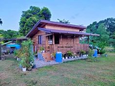 a small wooden house sitting on top of a lush green field with lots of trees