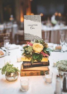 a table topped with books and flowers on top of each other next to candle holders