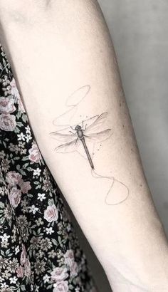 a woman's arm with a dragonfly tattoo on the back of her arm